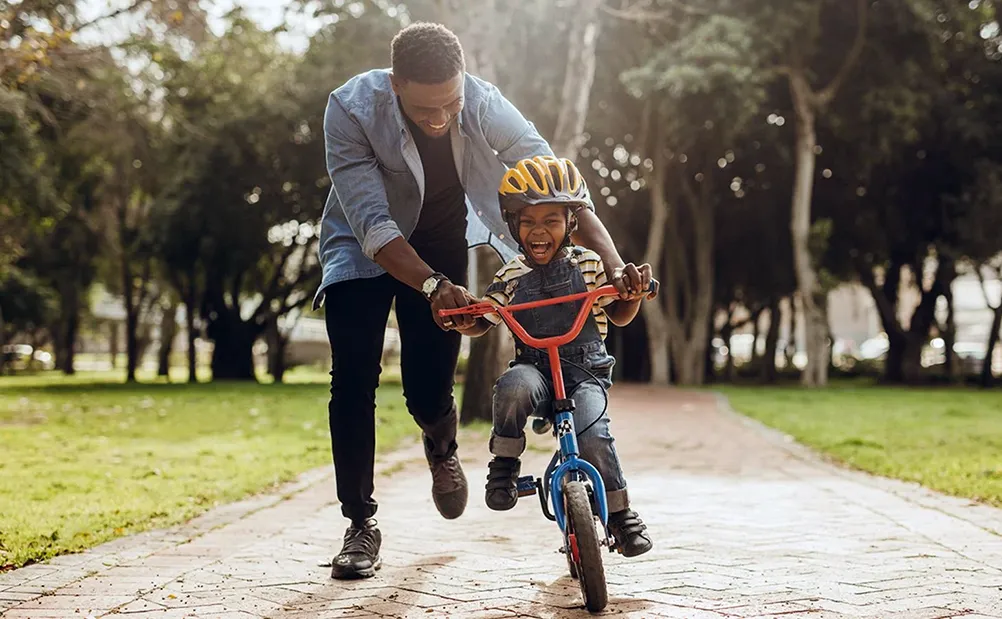 pai ensinando o filho a andar de bicicleta