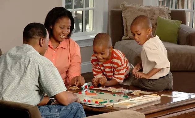 pais e filhos brincando de jogo de tabuleiro