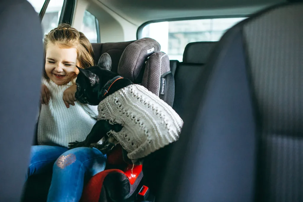 Menina brincando com o cachorrinho durante viagem de carro