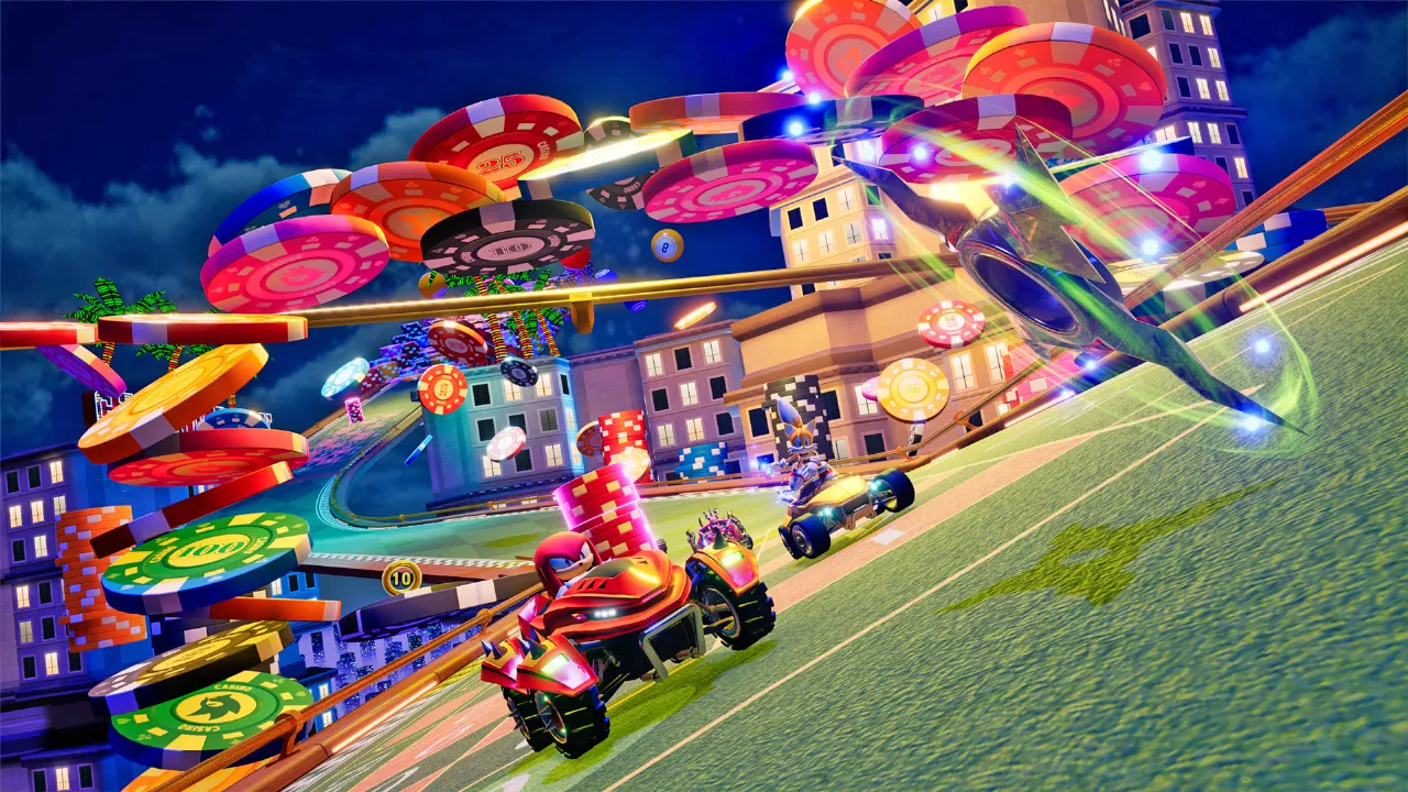 Knuckles em um veículo vermelho e Tails logo atrás em um veículo amarelo correm em uma pista vibrante e colorida, cheia de fichas de cassino gigantes, no jogo Sonic Racing: CrossWorlds.